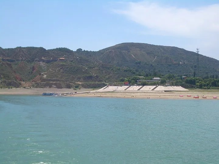 A reservoir shoreline with terraced hills and a ferry terminal in Linxia County