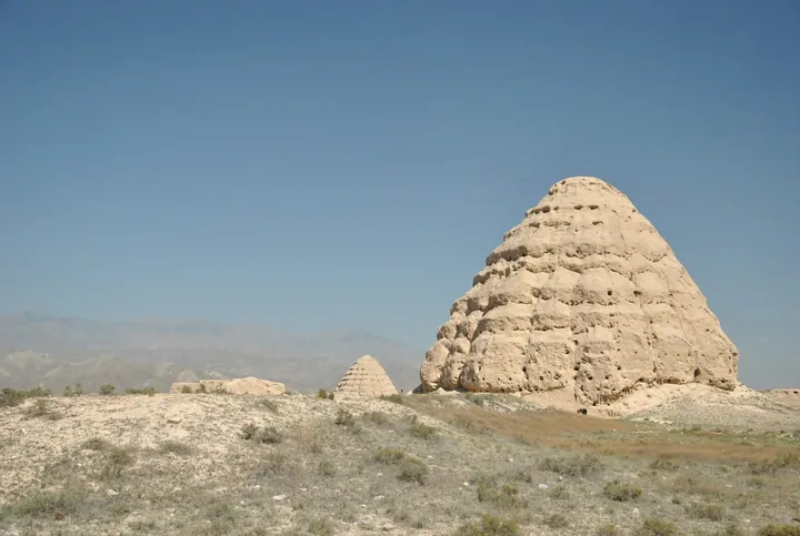 Two large earthen mausoleum mounds under blue sky in Xixia District