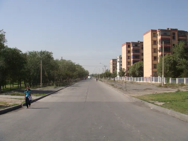 A quiet street with apartment buildings and trees in Toutunhe District
