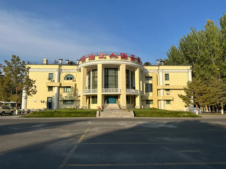 Symmetrical yellow colonnaded building under a blue sky in Dushanzi District