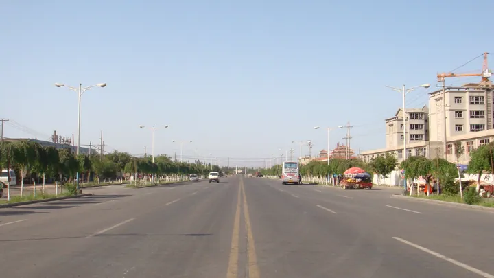 Wide street with trucks, cars and buildings in Toksun County, Turpan