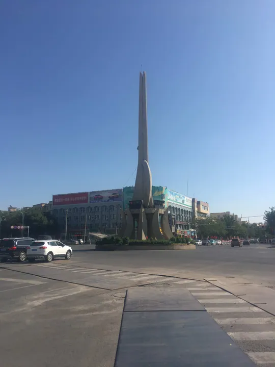 A tall abstract horse-themed monument at a roundabout in downtown Changji