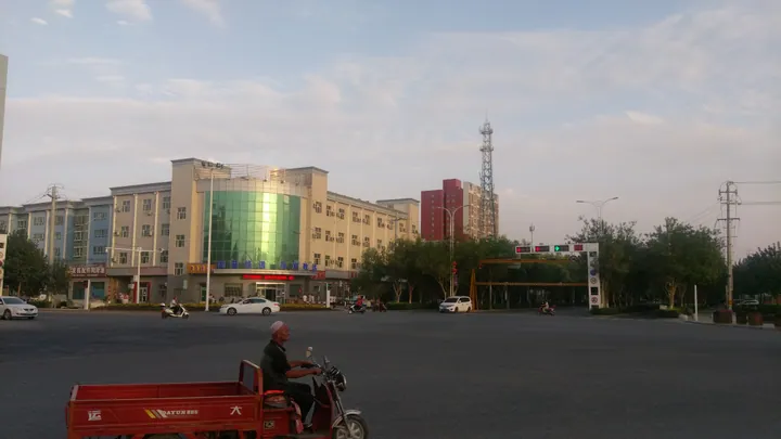 A street with buildings and a person riding a tricycle at dusk
