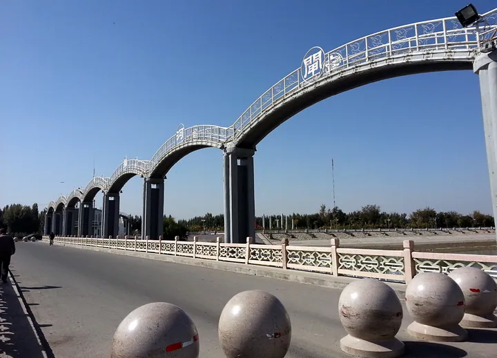 An arched pedestrian bridge crossing a river in downtown Karasahr, Yanqi