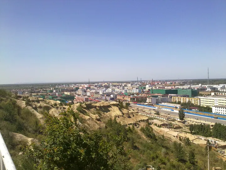Hillside overlook with eroded slopes in the foreground and a city skyline beyond
