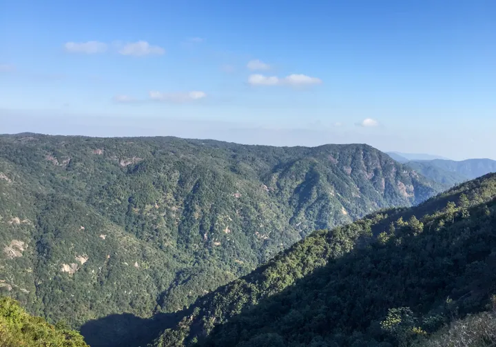 Layered green mountain ridges under blue sky at Guling