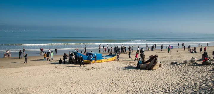 Sandy beach with visitors and a fishing boat at Liu'ao Feicui Bay