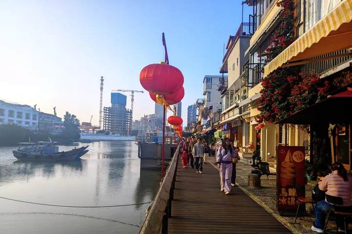 Waterfront boardwalk lined with red lanterns and pedestrians at Shapowei, Xiamen
