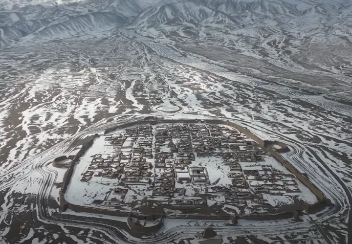 Aerial view of an oval walled town covered in snow