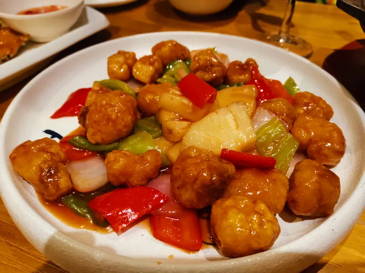 Plate of battered sweet and sour pork with pineapple and peppers