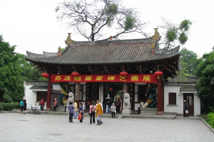A traditional temple gate hall with stone lions and visitors