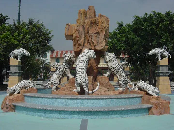 A fountain plaza with several white tiger statues arranged around a rock formation