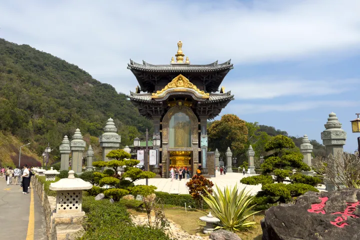 Ornate gilded pavilion housing a four-faced Guanyin statue on a mountainside
