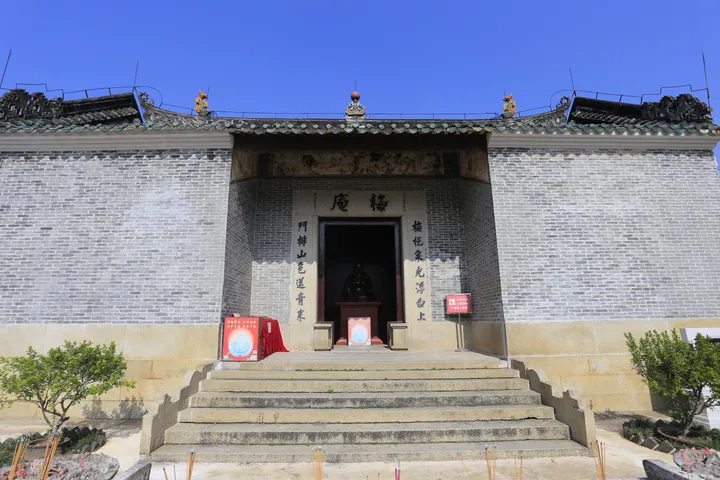 A grey brick temple facade with a shrine visible through the entrance