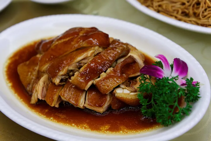 Glossy brown soy-sauce-braised chicken pieces on a white plate