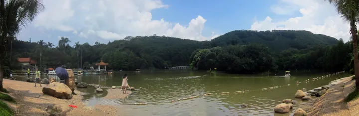 Panoramic view of Lake Xian surrounded by wooded hills in the botanical garden