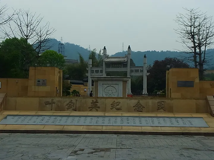 Stone memorial wall with large inscribed characters leading to a traditional gateway