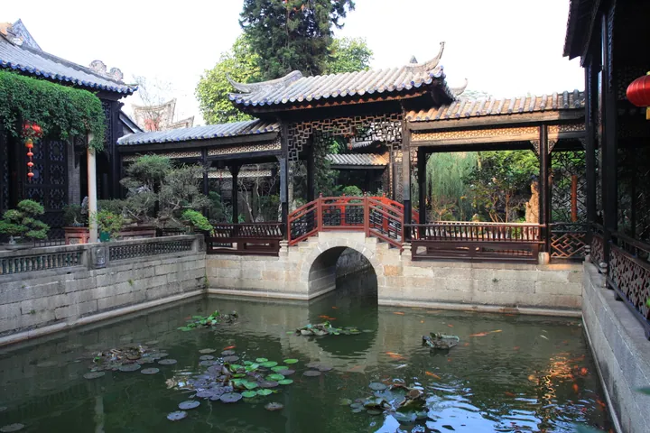 Koi pond with an arched red bridge and pavilions at Yuyin Garden