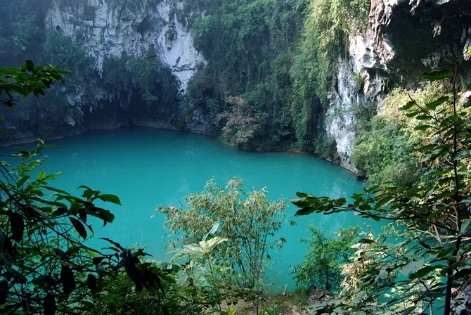 Turquoise karst sinkhole lake surrounded by cliffs at Sanmenhai