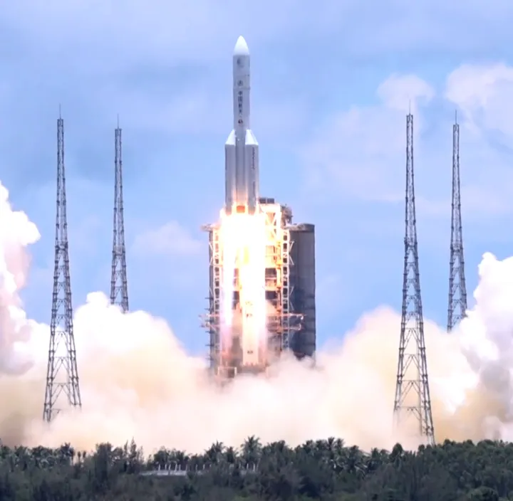 Rocket launch with fire and smoke between launch towers at Wenchang Space Launch Site