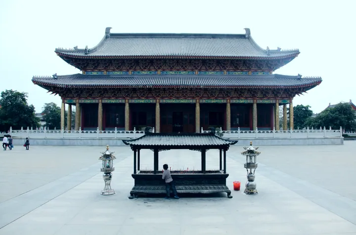 A traditional Chinese temple hall with an incense burner in the courtyard