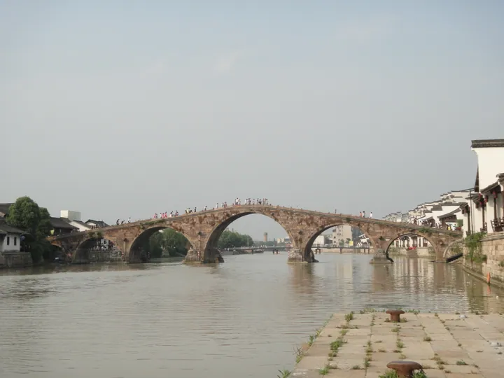 Multi-arched stone bridge over a canal lined with old town buildings