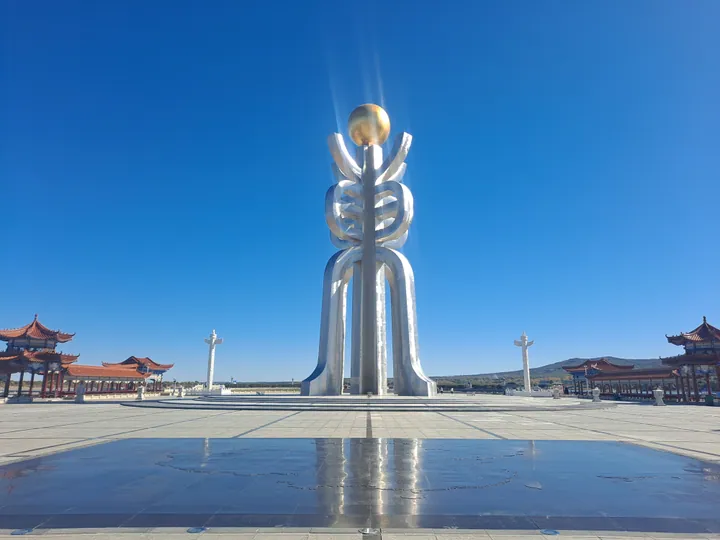 Tall metallic monument sculpture at Dongji Square under a clear blue sky