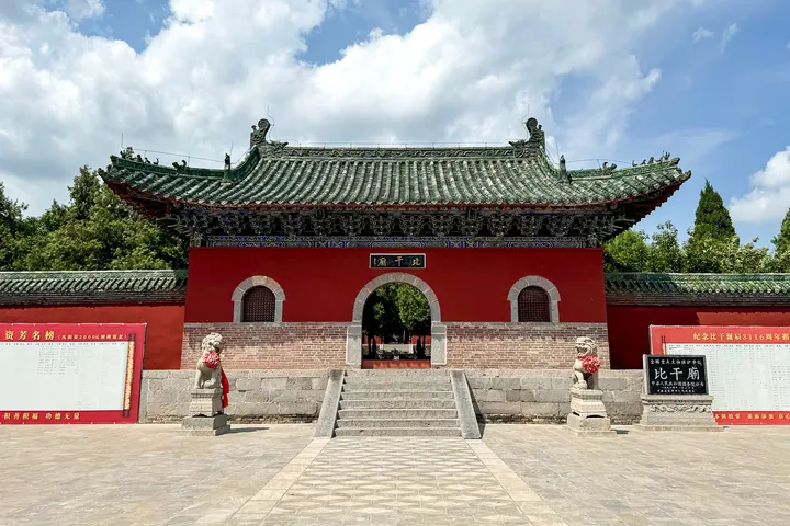 Red-walled temple gate hall with stone lions and Bi Gan Temple signboard