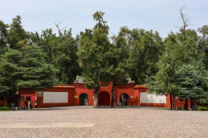 Red gate flanked by cypress trees at the entrance to Emperor Guangwu's mausoleum