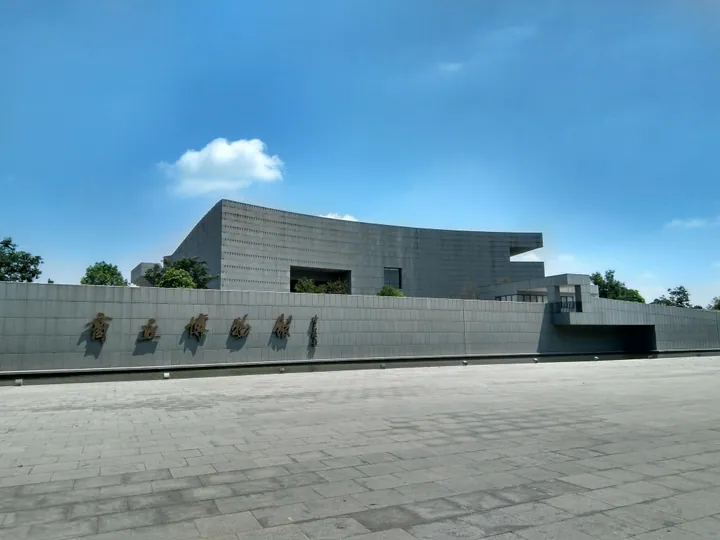 Modern curved stone-clad exterior of Shangqiu Museum under a blue sky