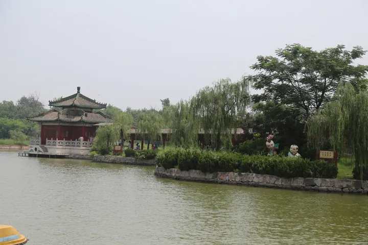 Red-roofed pavilion beside a lake, framed by willow trees, in Iron Pagoda Park