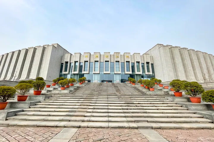 Wide stone staircase leading up to the Pingyuan Museum building with potted trees