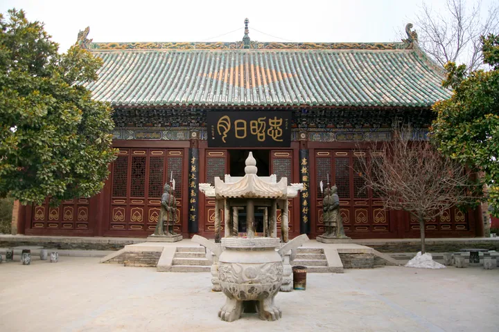 Temple hall with a large incense burner and guardian statues in front