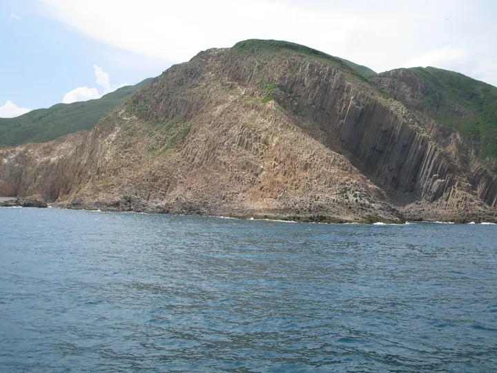 Cliff of hexagonal volcanic rock columns rising from the sea