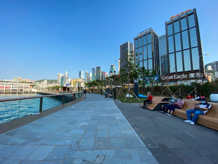Waterfront promenade with benches and city towers in Wan Chai