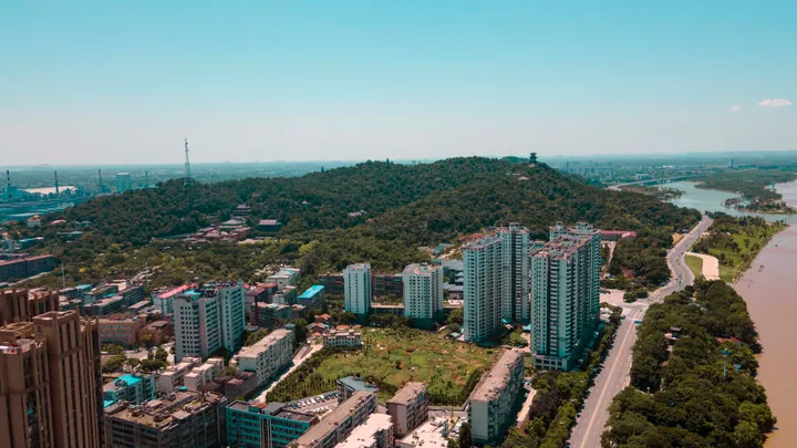 Aerial view of the forested Xishan hill and hilltop pavilion in Ezhou, Hubei, beside the river