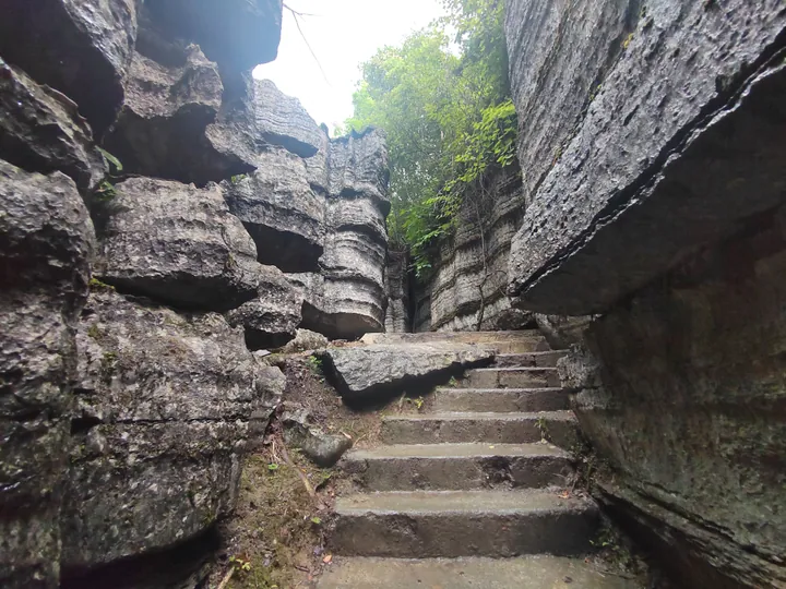 Narrow stone staircase between tall karst rock walls at Suobuya Stone Forest