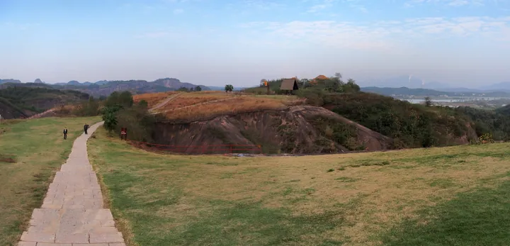 Open grassy hilltop path with rock formations at Feitian Mountain Scenic Area