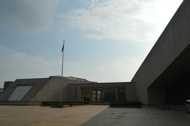 Angular concrete facade and forecourt of the Hunan Museum of Geology with a flagpole