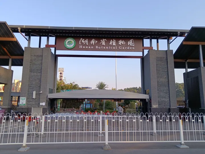Entrance archway signed 'Hunan Botanical Garden' with ticket barriers in front