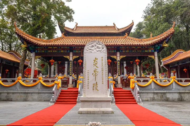 Stone stele inscribed 炎帝陵 in front of an ornate red-and-gold hall, with red carpet leading up to it