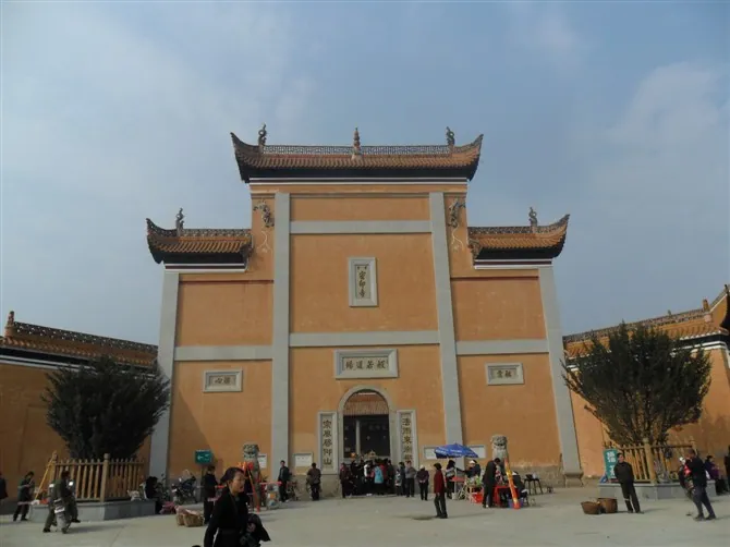 A traditional Chinese temple gate building under a blue sky with visitors