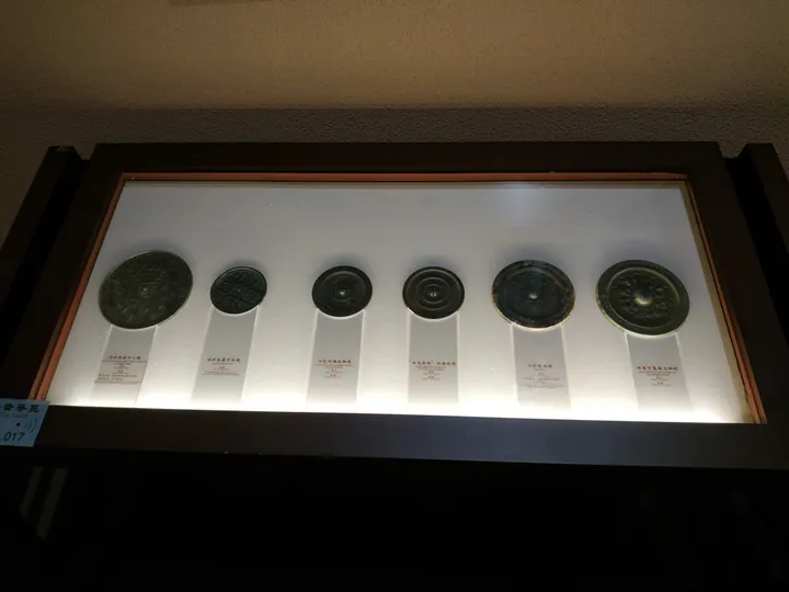 Several ancient bronze mirrors arranged in a museum display case