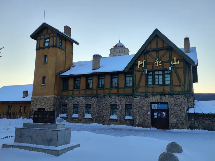 Snow-covered Arxan Railway Station building with a tower and timber-frame gable