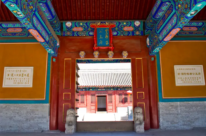 A colourfully painted timber gate with stone lions at the entrance to Hohhot City Museum, with a 公主府 plaque above