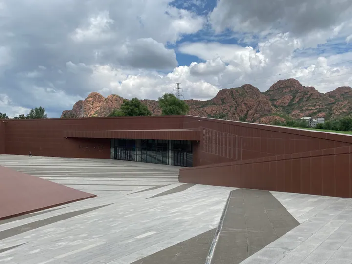 Exterior of the Hongshan Culture Museum with red rocky hills in the background