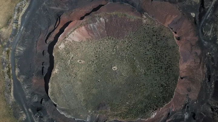 Overhead aerial view of a circular volcanic crater filled with vegetation