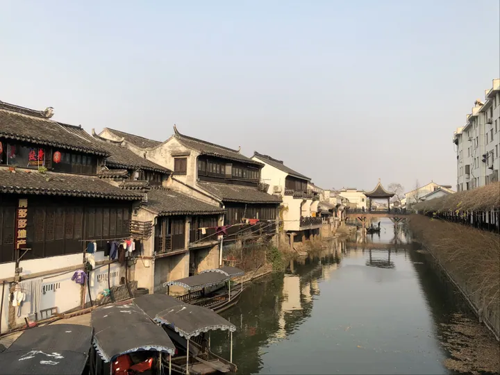Canal-side old town with boats and a distant bridge pavilion