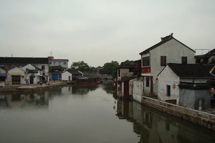 Traditional whitewashed houses along a canal with lanterns and boats