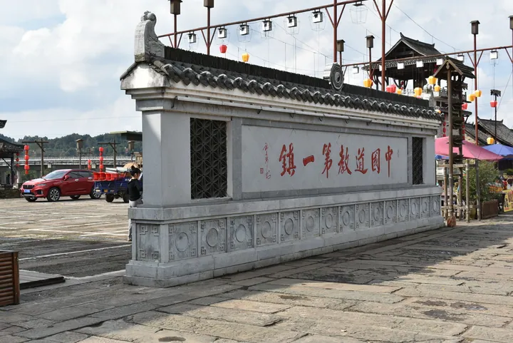 Carved stone wall with red Chinese text at the entrance plaza of Shangqing town